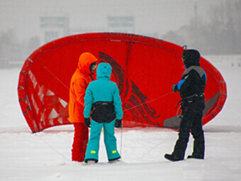 три человека на фоне красного кайта