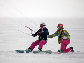 инструктор по сноукайтингу учит ехать на сноуборде